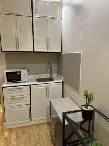 a kitchen with white cabinets and a table and a microwave at شقة جميلة بغرفتين نوم ودخول ذاتي 106B in Riyadh