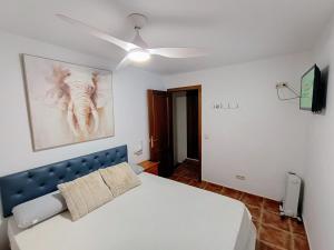 1 dormitorio con cama blanca y ventilador de techo en Casa Rural Agua de Azahar Chimenea, en Zahara de la Sierra