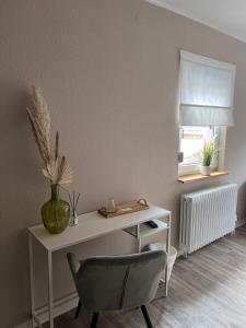 a white desk with a chair and a vase on it at Pension Krone Sternenfels in Sternenfels