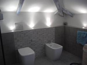 a bathroom with a toilet and a sink with lights at Appartamento romantico indipendente in Gaglianico +10 photos