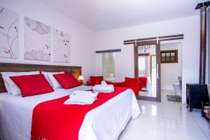 1 dormitorio con 1 cama grande con almohadas rojas en Pousada das Videiras, en Monte Verde