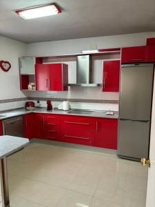 una cocina con armarios rojos y electrodomésticos de acero inoxidable en Casa Ubedí en pleno casco histórico en Úbeda