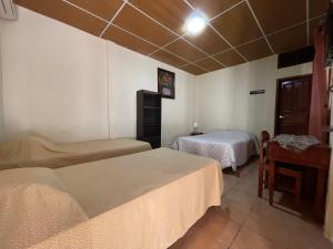a hotel room with two beds and a table at Hotel Vizcaino in Matagalpa