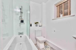 a white bathroom with a toilet and a bath tub at Next to Headingley Stadium - Perfect for Families & Work - Contact us for Better Offers! in Headingley