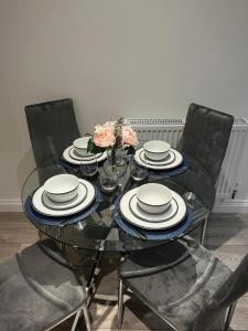 a glass table with chairs and plates and flowers on it at Newly built one bedroom flat in Kidlington, Oxfordshire in Kidlington +11 photos