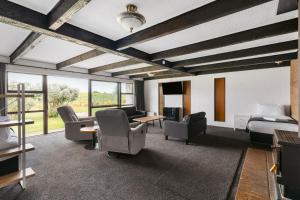 a hotel room with a bed and chairs and windows at Rolleston Motel Thames - Wenzel Motels in Thames