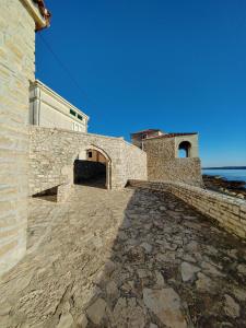 a stone building with a stone walkway next to the ocean at Apartment Kaplja in Novigrad Istria
