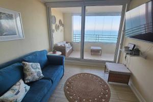 salon z niebieską kanapą i balkonem w obiekcie Frente a la playa. Vista al mar. w mieście Concón