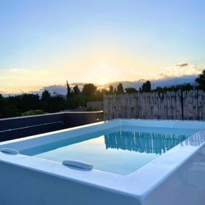 uma piscina com um pôr-do-sol ao fundo em La Cava Apartments em Luján de Cuyo