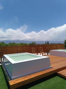 bañera de hidromasaje en una terraza de madera con mesa en La Cava Apartments en Luján de Cuyo