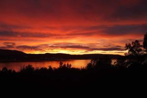 a sunset over a lake with a red sky at Leilighet med fantastisk utsikt. in Tromsø