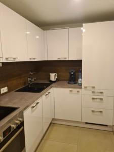 a white kitchen with white cabinets and a sink at WellandHome Aalen - Private Deluxe Apartment in Aalen