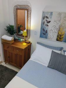 a bedroom with a bed and a mirror on a dresser at Suíte Girassol Cama & Café - Centro, Marechal Floriano-ES in Marechal Floriano