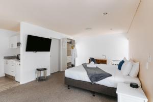 a bedroom with a large bed and a flat screen tv at Rolleston Motel Thames - Wenzel Motels in Thames