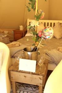 a table with wine glasses and a bucket of flowers at Hopgarden Glamping Exclusive site hire - Sleep up to 50 guests in Wadhurst