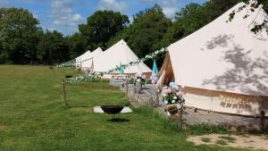 Hopgarden Glamping Exclusive site hire - Sleep up to 50 guests في Wadhurst: صف من الخيام البيضاء في حقل