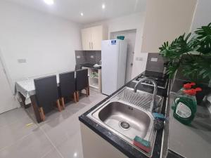 uma cozinha com um lavatório e uma cozinha com cadeiras em Cheerful 4/5 bed house - Heathrow em West Drayton