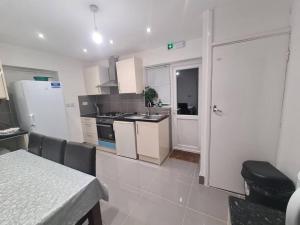 a kitchen with white appliances and a table in a room at Cheerful 4/5 bed house - Heathrow in West Drayton