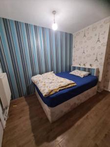 um quarto com uma cama com lençóis azuis e papel de parede em Cheerful 4/5 bed house - Heathrow em West Drayton