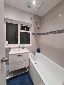 a white bathroom with a tub and a sink and a bath tub at Cheerful 4/5 bed house - Heathrow in West Drayton