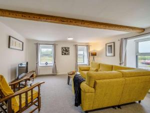 een woonkamer met een gele bank en ramen bij 2 Bed in Cockermouth 85680 in Bridekirk