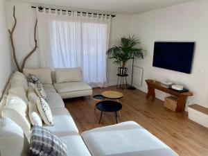 ein Wohnzimmer mit einem weißen Sofa und einem Flachbild-TV in der Unterkunft Appartement d'exception, vue Saint-Tropez in Saint-Tropez