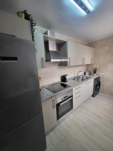 una cucina con armadi bianchi, lavandino e lavastoviglie di Appartement centre ville Malaga a Málaga
