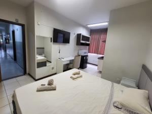 a bedroom with a bed with two towels on it at Hotel Avelar in Ribeirão das Neves