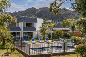 a house with a swimming pool with blue chairs at Avalon Motel Thames - Wenzel Motels in Thames