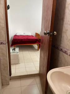 baño con lavabo y manta roja en un banco en Yachanapaq Wasi I en Huanta