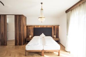 a bedroom with a bed and a chandelier at Romantik Hotel Jagdhof in Caldaro