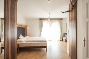 a bedroom with a bed and a large window at Romantik Hotel Jagdhof in Caldaro