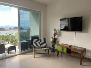 a living room with a tv and a chair and a table at Punta Esmeralda by Punta Leona in Puntarenas