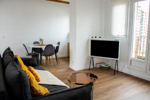 a living room with a black couch and a tv at Apartamento panorámico in Charenton-le-Pont