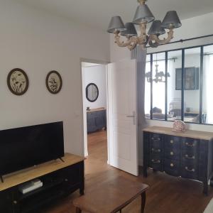 a living room with a flat screen tv and a table at Spacieux duplex en plein centre-ville de Fontainebleau in Fontainebleau