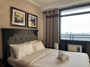 Gramercy Residences 46th Floor 1 Bedroom Sunset View في مانيلا: غرفة نوم بسرير مع نافذة كبيرة