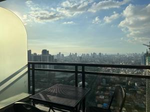 einen Tisch und Stühle auf einem Balkon mit Stadtblick in der Unterkunft Gramercy Residences 46th Floor 1 Bedroom Sunset View in Manila