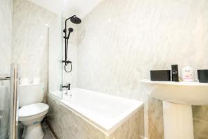 a white bathroom with a toilet and a sink at Benoît Apartments in Manchester