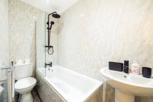a bathroom with a tub and a toilet and a sink at Benoît Apartments in Manchester