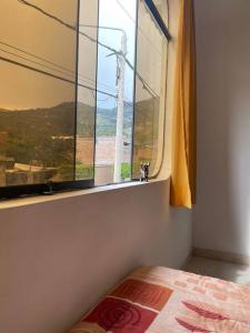 a bedroom with a window with a dog looking out at Yachanapaq Wasi II in Huanta