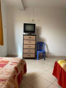 a bedroom with a tv on a dresser and a blue chair at Yachanapaq Wasi II in Huanta