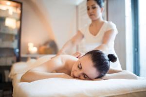 una mujer acostada en una cama en una sala de masajes en Romantik Hotel Jagdhof en Caldaro