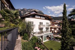 a large white house with mountains in the background at Romantik Hotel Jagdhof in Caldaro
