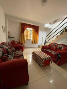 a living room with red couches and a staircase at Yachanapaq Wasi III in Huanta