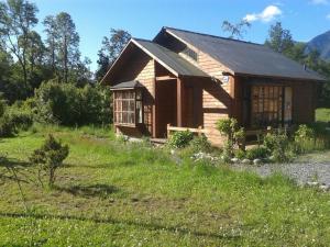 una pequeña casa de madera en un campo de hierba en Cabañas Bosques del Claro, en Pucón