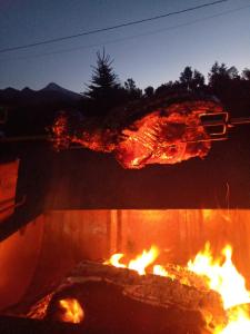 Ein Stück Fleisch kocht über einem Feuer in der Unterkunft Cabañas Bosques del Claro in Pucón