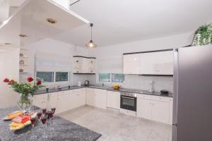 a kitchen with white cabinets and a glass table at Villa Cervus Dianae in Kallithea Rhodes