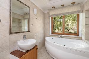 bagno con vasca, lavandino e specchio di Jacuzzi apartments SELF CHECK-IN 24/7 by H&H a Vilnius