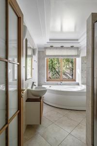 bagno con vasca, lavandino e finestra di Jacuzzi apartments SELF CHECK-IN 24/7 by H&H a Vilnius