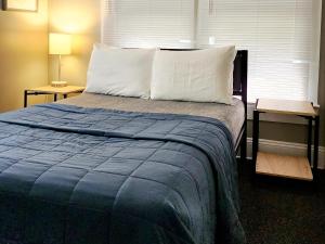 1 cama con manta azul y almohadas blancas en TWO BEDROOM HOME IN BEAUTIFUL DOWNTOWN LAKELAND, en Lakeland